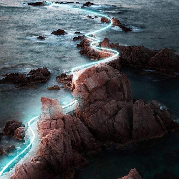 The 2025 Environmental Sustainability Report cover featuring an aerial view of an ethereal blue light lining a pathway carved out of rock leading into an ocean.