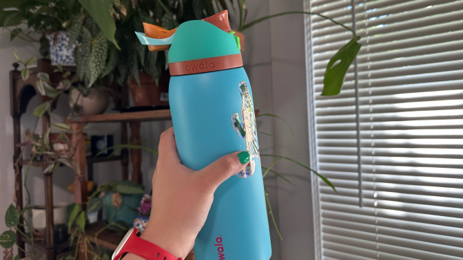 A person's hand holding an Owala FreeSip water bottle