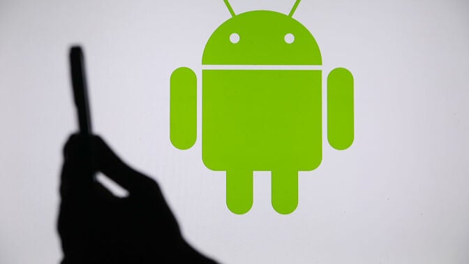 Android logo with smartphone in person's hand next to it