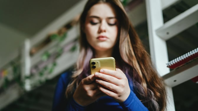 Girl looks down at phone in her hands.