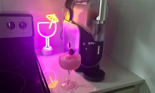 the ninja slushi on a countertop next to a frozen drink and a neon sign