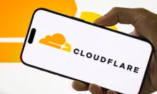 A person holds a smartphone displaying the logo of Cloudflare Inc. (NYSE: NET), an American web infrastructure and website security company, with the company's cloud logo visible in the background, on July 29, 2025 in Chongqing, China.