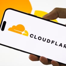 A person holds a smartphone displaying the logo of Cloudflare Inc. (NYSE: NET), an American web infrastructure and website security company, with the company's cloud logo visible in the background, on July 29, 2025 in Chongqing, China.