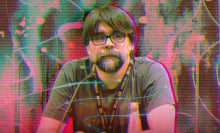 A man sits behind a podium with a microphone in front of him.