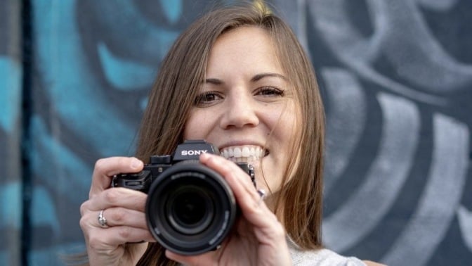 A person smiling and holding a camera.