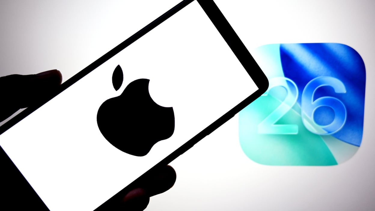  Apple logo is seen displayed on a smartphone with an IOS 26 logo in the background