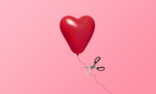 Red heart balloon floating in air while attached to a string on a pink background with with a scissor about to let it go