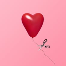 Red heart balloon floating in air while attached to a string on a pink background with with a scissor about to let it go
