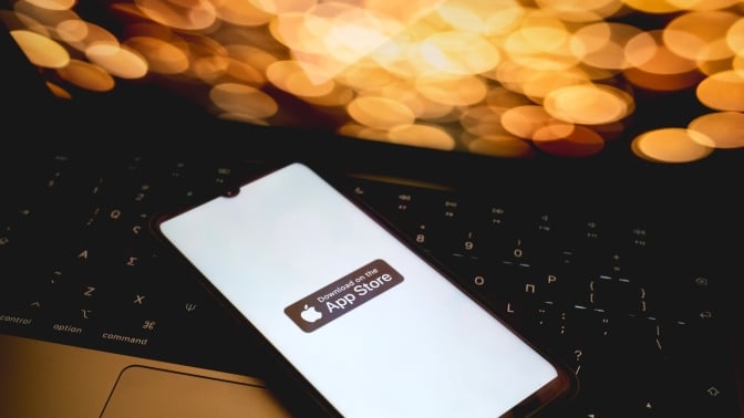 The App store on an iPhone atop a laptop. 