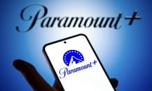 A hand holding a phone with the Paramount+ logo on it.