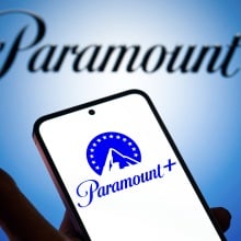 A hand holding a phone with the Paramount+ logo on it.