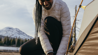 Person tying shoe while wearing gray puffer coat