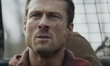 A man with blood on his face looks at something off-camera.