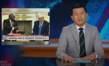 A man in a suit sits behind a talk show desk. In the top-left is an image of two other men in suits in the Oval office.