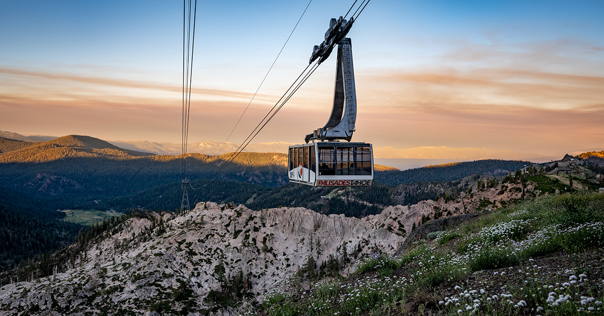 An expansive view of a sunset over Lake Tahoe with the tram of Palisades Tahoe