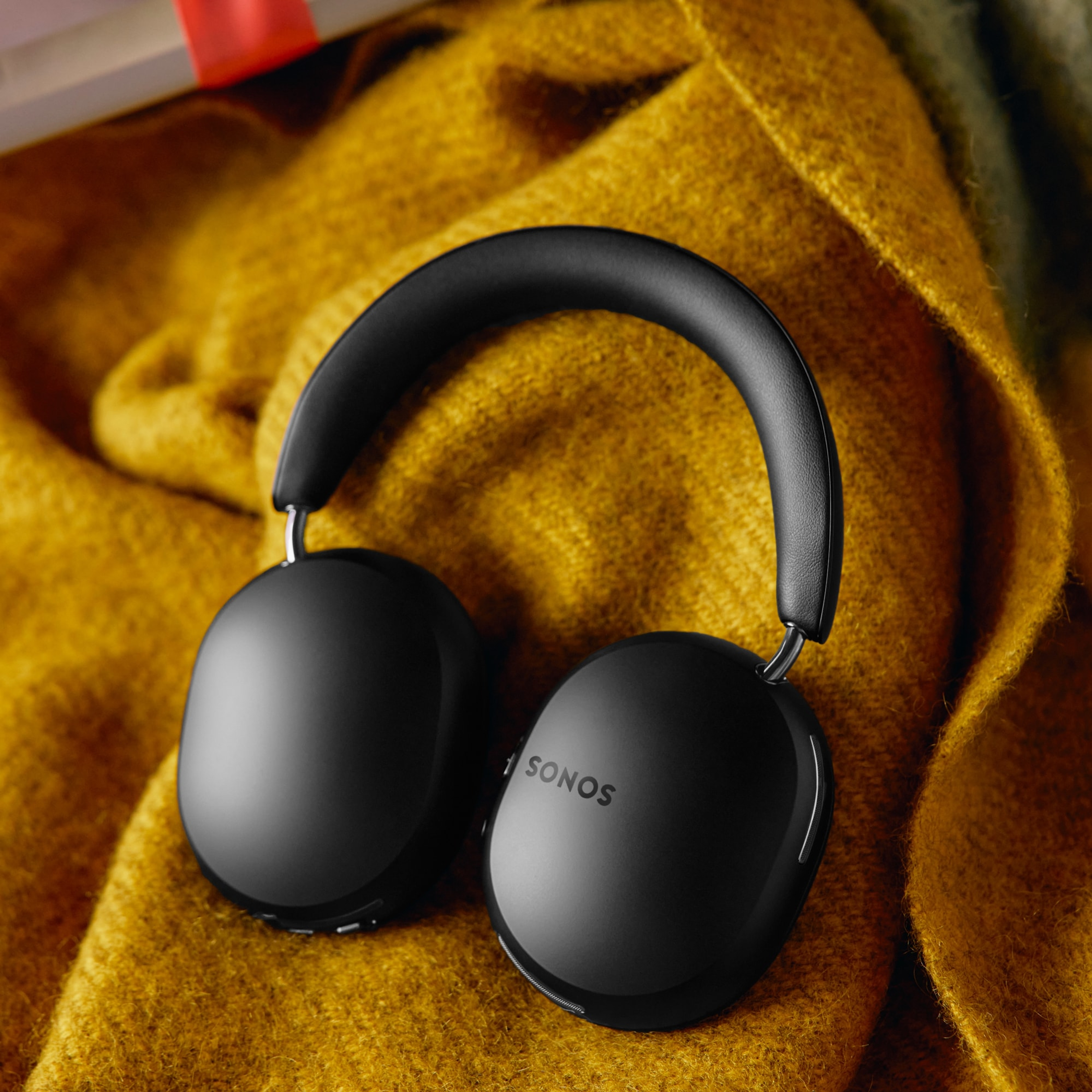 A pair of black Sonos Ace headphones on a yellow blanket