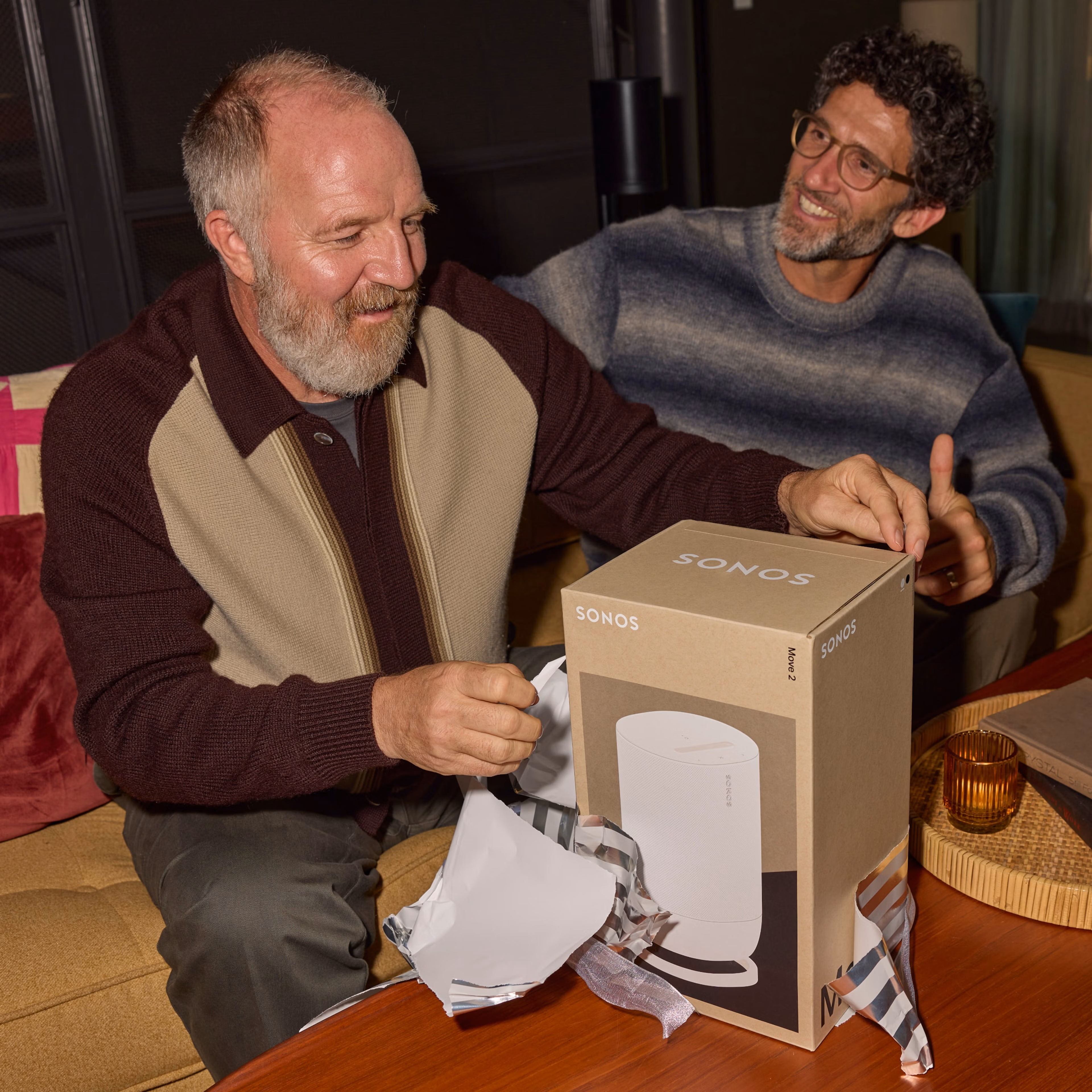 Two people smiling and opening a gift wrapped Sonos Move 2